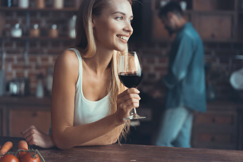 A woman holding a glass of red wine and smiling