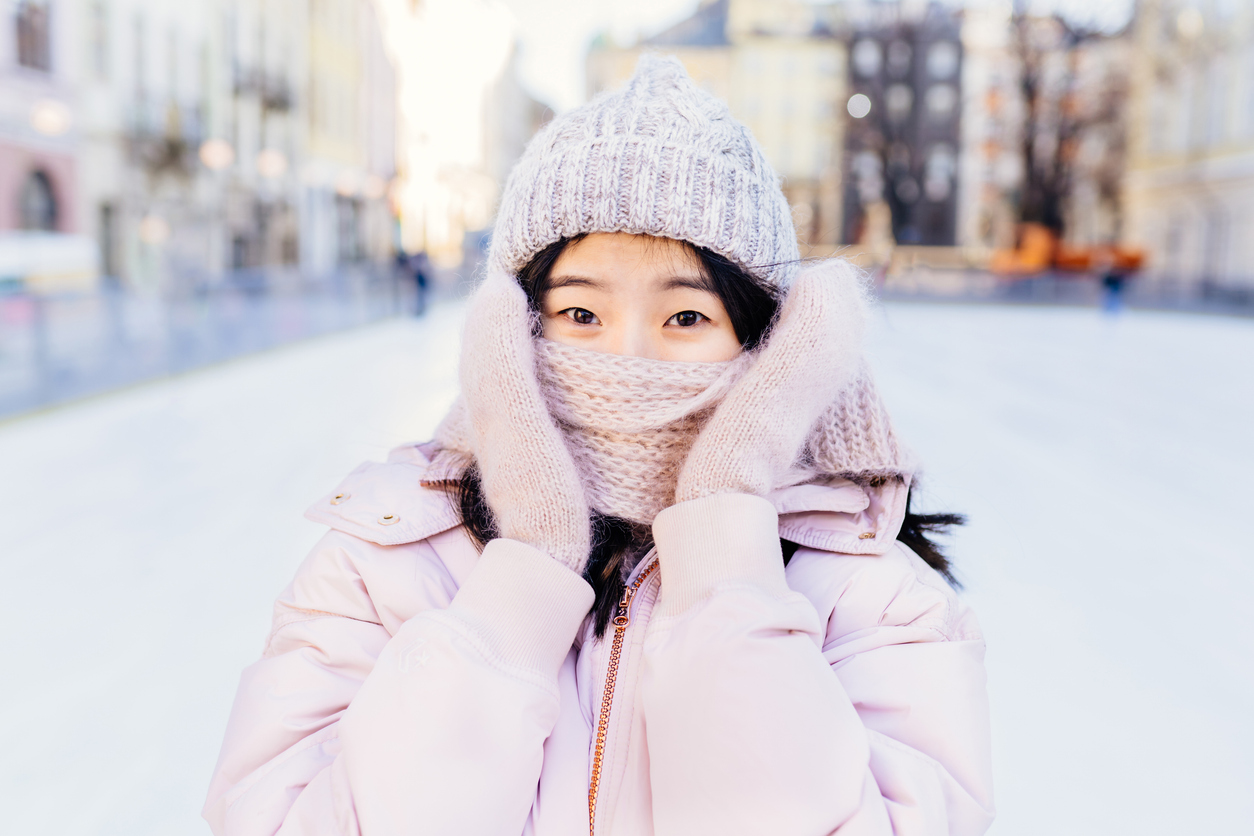 Woman outside in winter wearing a scarf over her mouth to protect her teeth from hurting in cold weather