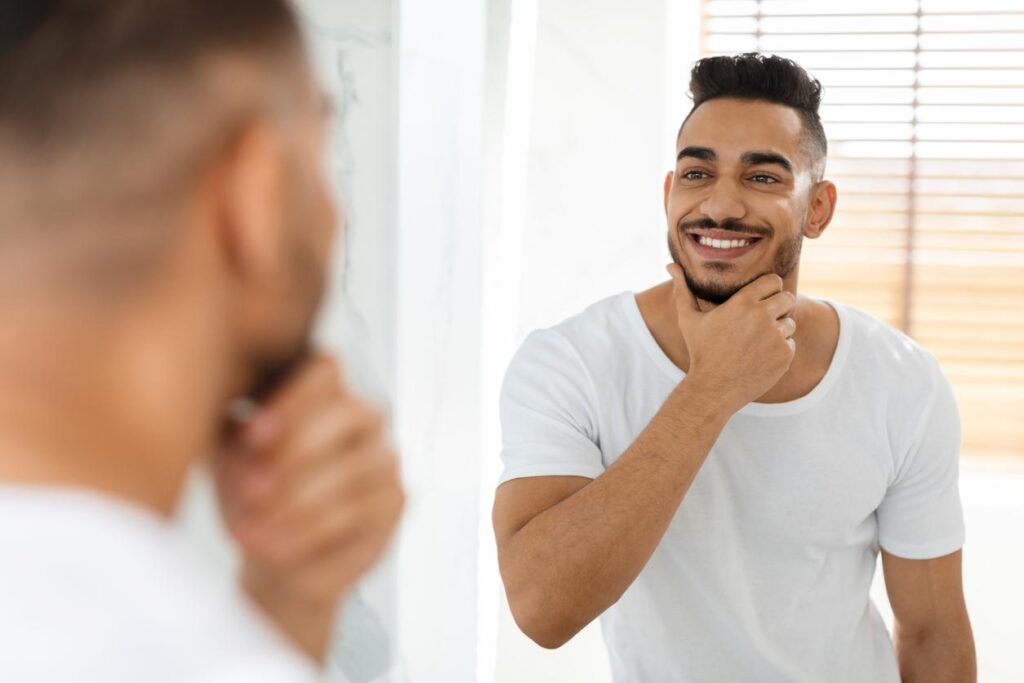 A man looking at his smile in the mirror